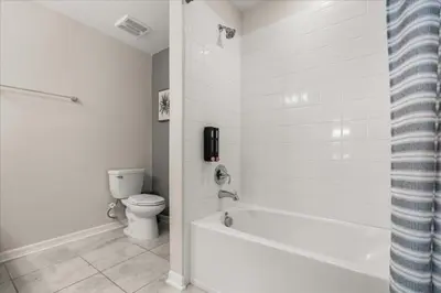 a white bathroom with a toilet and a bath tub at 3 Bedrooms 2 Bathrooms Storey Lake 3141-306 in Kissimmee