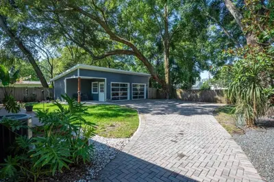 a small blue house with a brick driveway at Massive 3 bedroom with large backyard in Orlando