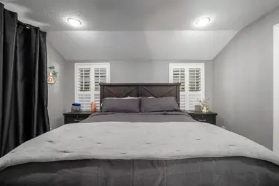 a bedroom with a large bed and two windows at Massive 3 bedroom with large backyard in Orlando