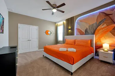 a bedroom with an orange bed with a painting on the wall at Luxury and Sophisticated 15 BR ensuite in Kissimmee