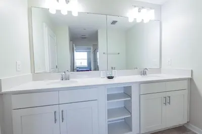 a white bathroom with two sinks and a large mirror at Comfortable 2BR Condo w Lake Views in Kissimmee