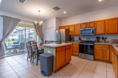 a kitchen with wooden cabinets and a table with chairs at 8512 Emerald Island in Kissimmee