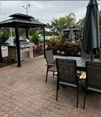 a patio with a grill and an umbrella and chairs at Westgate Towers in Orlando