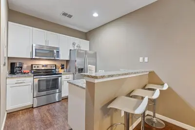 a kitchen with white cabinets and a counter with stools at Amzing location 3BDR House - 8980 in Kissimmee