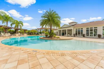 a large swimming pool with a palm tree in front of a building at Amzing location 3BDR House - 8980 in Kissimmee