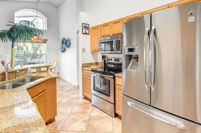 a kitchen with stainless steel appliances and wooden cabinets at 3 Mi to Disney World Poolside Oasis with Game Room in Kissimmee