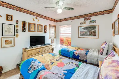 a bedroom with two beds and a flat screen tv at 3 Mi to Disney World Poolside Oasis with Game Room in Kissimmee