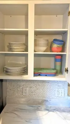 a white cabinet filled with plates and bowls at Modern 3BR Home 10 Min from MCO in Orlando
