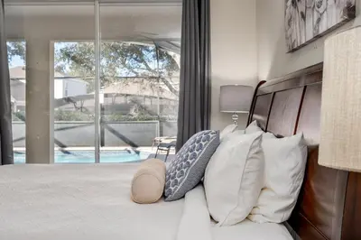 a bedroom with a bed and a window with a pool at Free Waterpark|Game Room|Near Dis! in Orlando