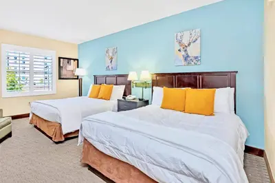 two beds in a room with blue walls and yellow pillows at Studio with Hot Tub & Pool Near Universal Studios in Orlando