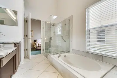 a bathroom with a tub and a glass shower at 12 Mi to Disney Secluded Family Home with Pool in Kissimmee