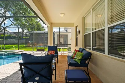 a screened in porch with chairs and a pool at Large house at Windsor Hills Resort in Orlando