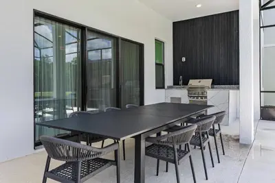 a dining room with a black table and chairs at Brand NEW 11 Bedrooms At Sonoma in Kissimmee