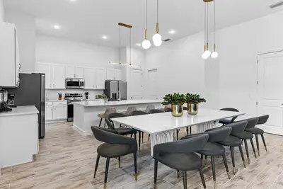 a white kitchen with a white table and chairs at Brand NEW 11 Bedrooms At Sonoma in Kissimmee