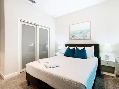 a white bedroom with a large bed with blue pillows at Amazing 5BR Townhouse near Disney - Private Pool in Kissimmee