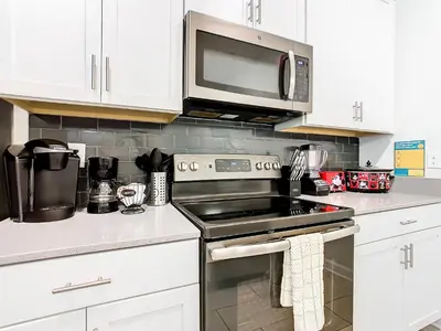 a kitchen with a stove and a microwave at Amazing 5BR Townhouse near Disney - Private Pool in Kissimmee