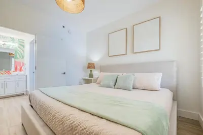 a white bedroom with a large bed with two pictures on the wall at Brand new - near Epic Universe & Universal Studios in Orlando
