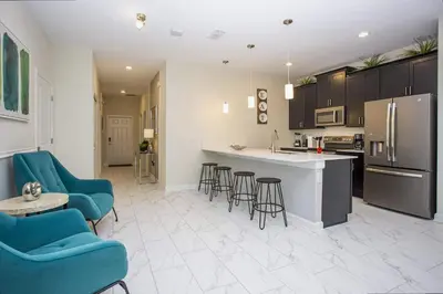 a large kitchen with blue chairs and a counter top at 5BR Private Pool Resort Amenities Near Disney in Kissimmee