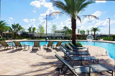 a swimming pool with chairs and a palm tree at 5BR Private Pool Resort Amenities Near Disney in Kissimmee