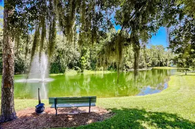 a park bench in front of a pond with a fountain at The Palms 1st floor By Pool, Fully Stocked 5 stars in Kissimmee