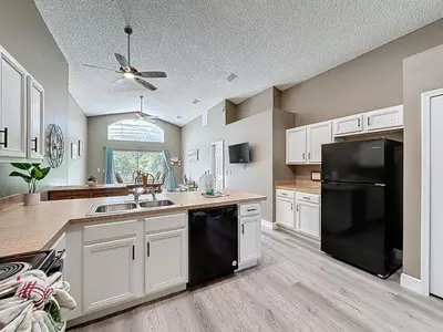 a kitchen with white cabinets and a black refrigerator at Terra Verde Resort 4 Bed Pool Spa Villa villa in Kissimmee