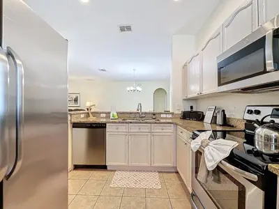 a kitchen with white cabinets and a stainless steel refrigerator at Walk to Silver Spurs Rodeo and Heritage Park home in Kissimmee