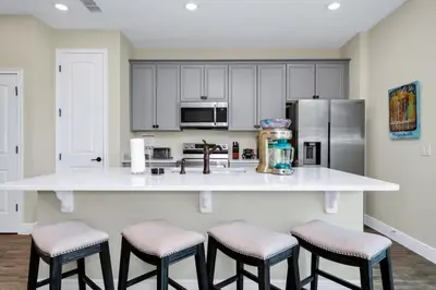 a kitchen with a counter with four stools at Blue Sky Hideaway Villa Near Disney With Margaritaville Resort & Island H20 Waterpark Access - 2921Cs in Orlando