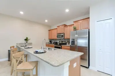 a kitchen with wooden cabinets and a stainless steel refrigerator at 4815 Townhome com Piscina Privada– Storey Lake in Kissimmee