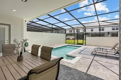 a house with a pool and a patio with chairs at Brand New 05 Bedrooms At Windsor Cay in Orlando