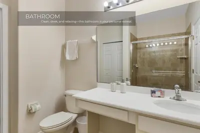 a bathroom with a toilet and a sink and a mirror at Charming 3-Bedroom Home in Gated Oakwater Resort in Orlando
