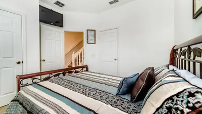 a bed in a bedroom with white walls at OP7652 Windsor Hills 3 Bedroom Private Pool Townhome in Orlando