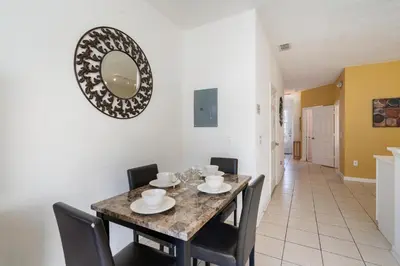 a dining room with a table and chairs and a mirror at OP7678 Windsor Hills 3 Bedroom Private Pool Townhome in Orlando