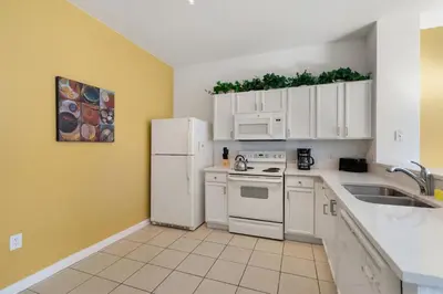 a kitchen with white cabinets and a white refrigerator at OP7678 Windsor Hills 3 Bedroom Private Pool Townhome in Orlando
