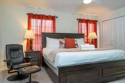 a bedroom with a large bed and a chair at Storey Lake 4 BR with private pool in Kissimmee