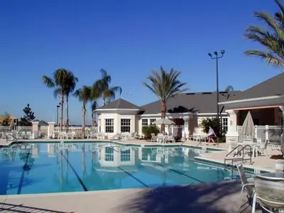 a large swimming pool with chairs and palm trees at Windsor Palm 3 bed Condo in Kissimmee