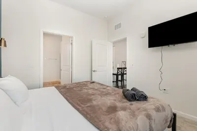 a white bedroom with a large bed and a flat screen tv at Orlando 2BR Retreat 3 Beds Near Disney&Universal in Orlando