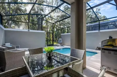 an indoor patio with a glass table and a swimming pool at Casa 5Q c/ Piscina e Temas Disney — Storey Lake in Kissimmee