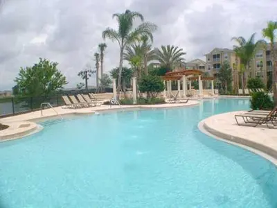 a large swimming pool with chairs and palm trees at Windsor Castle in Orlando