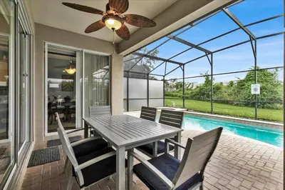 a patio with a table and chairs and a pool at MNL2702 Windsor Hills Resort Vacation Home in Orlando