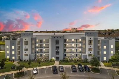 a large building with cars parked in a parking lot at 3 Bedrooms 2 Bathrooms Storey Lake 3131-406 in Kissimmee