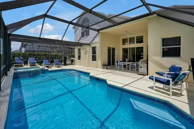 a swimming pool with chairs and a house at Windsor Palms Resort in Kissimmee