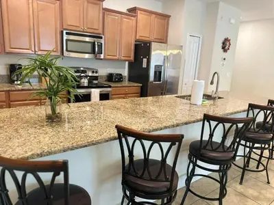 a kitchen with wooden cabinets and a island with bar stools at Casa 4 Quartos c/ Piscina Privativa – Storey Lake in Kissimmee