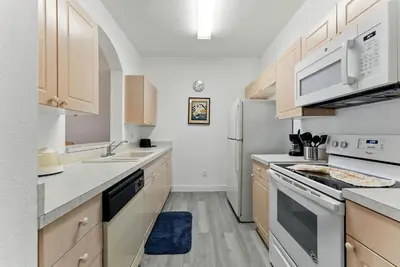 a kitchen with white appliances and wooden cabinets at 3BR Resort Condo Pool Balcony Near Disney in Kissimmee