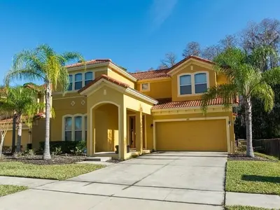 a yellow house with palm trees in front of it at 4 Bedrooms 5 Bathrooms Bella Vida 871Mb in Kissimmee