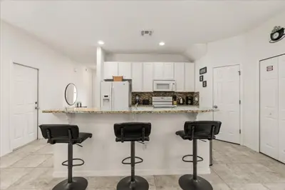 a kitchen with white cabinets and black bar stools at 4 Bedrooms 5 Bathrooms Bella Vida 871Mb in Kissimmee