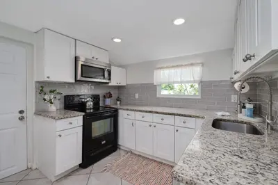 a kitchen with white cabinets and a sink and a microwave at Winter Park Gem 2BR Near Parks 3MI to Downtown in Orlando