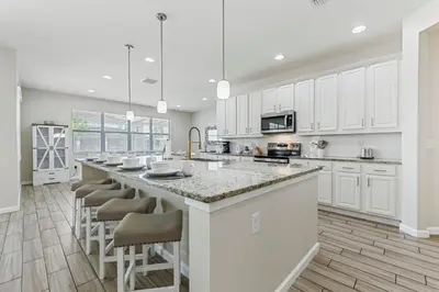 a kitchen with white cabinets and a large island with bar stools at 2605 Yountville Ave in Kissimmee