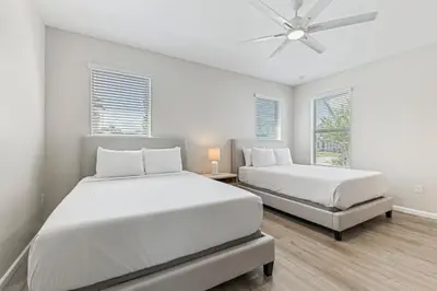 two beds in a white room with a ceiling fan at 2605 Yountville Ave in Kissimmee