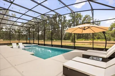 an indoor pool with an umbrella and chairs and a pool at 15 Bedrooms 16 Bathrooms Sonoma 4151 Sb in Kissimmee