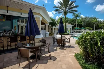 a patio with tables and chairs and umbrellas next to a pool at 4BRRenovateNO Resort feePrivate PoolDisney in Kissimmee